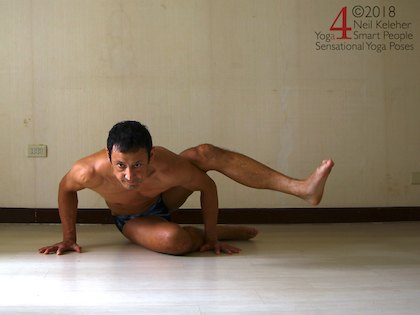 Astavakrasana preparation exercise, this is actually working towards a variation of eka pada koundinyasana. Elbows bent with one leg resting against the back of an arm. Neil Keleher. Sensational Yoga Poses.